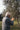 An elderly man plucks olives from a tree.