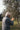 An elderly man plucks olives from a tree.