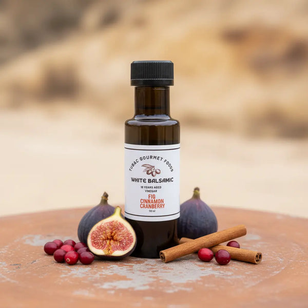 Fig Cinnamon Cranberry White Balsamic Vinegar bottle with figs, cranberries and cinnamon on terracotta surface