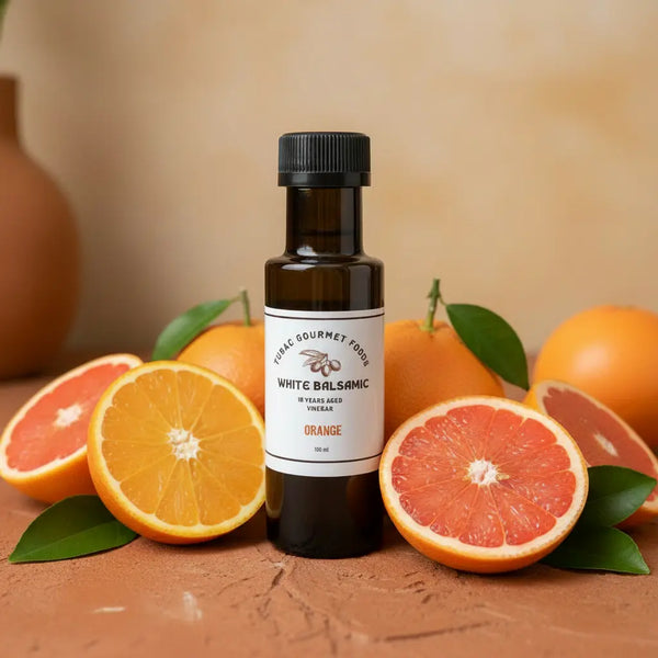 Orange White Balsamic Vinegar bottle with fresh oranges on terracotta surface