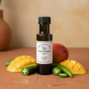 Jalapeno Mango White Balsamic Vinegar bottle with mango and jalapeños on terracotta surface