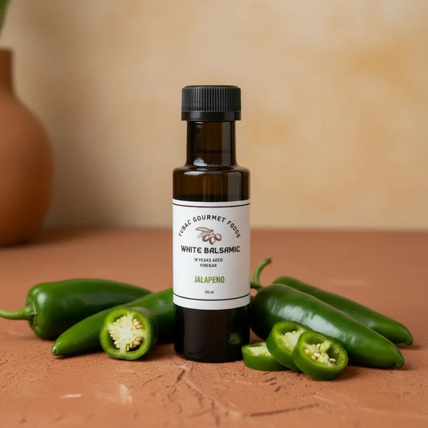 Jalapeno White Balsamic Vinegar bottle with fresh jalapeños on terracotta surface