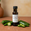 Jalapeno White Balsamic Vinegar bottle with fresh jalapeños on terracotta surface