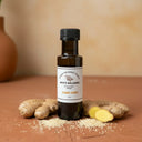 Sesame Ginger White Balsamic Vinegar bottle with ginger root and sesame seeds on terracotta surface