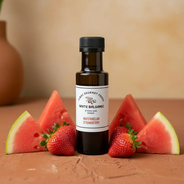 Watermelon Strawberry White Balsamic Vinegar bottle with watermelon and strawberries on terracotta surface