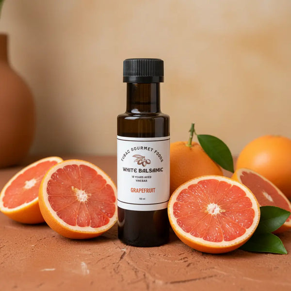 Grapefruit White Balsamic Vinegar bottle with fresh grapefruit on terracotta surface