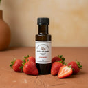 Strawberry White Balsamic Vinegar bottle with fresh strawberries on terracotta surface