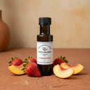 Strawberry Peach White Balsamic Vinegar bottle with fresh strawberries and peaches on terracotta surface