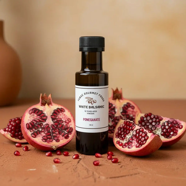 Pomegranate White Balsamic Vinegar bottle with fresh pomegranate on terracotta surface