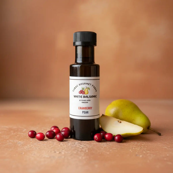 Cranberry Pear White Balsamic Vinegar bottle with cranberries and pear on terracotta surface