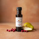 Cranberry Pear White Balsamic Vinegar bottle with cranberries and pear on terracotta surface