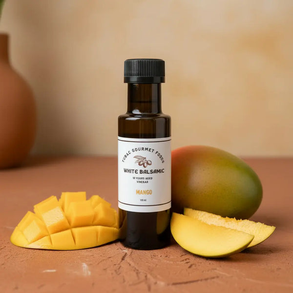 Mango White Balsamic Vinegar bottle with fresh mango on terracotta surface