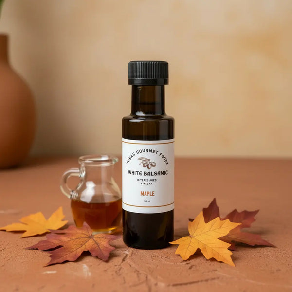 Maple White Balsamic Vinegar bottle with maple syrup and maple leaves on terracotta surface