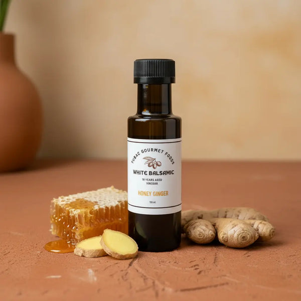 Honey Ginger White Balsamic Vinegar bottle with ginger and honeycomb on terracotta surface