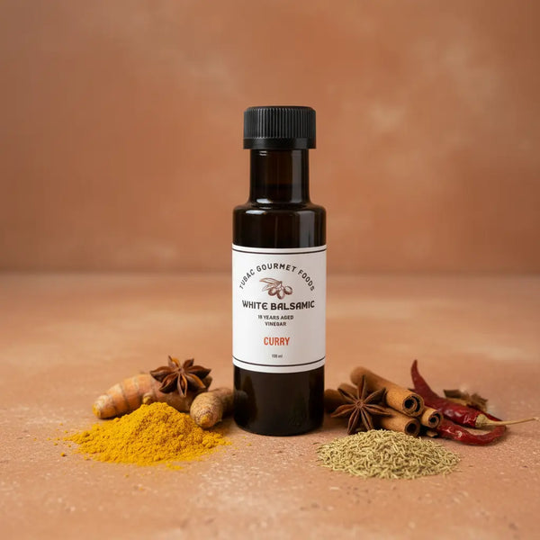 Curry White Balsamic Vinegar bottle with curry spices on terracotta surface