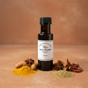 Curry White Balsamic Vinegar bottle with curry spices on terracotta surface