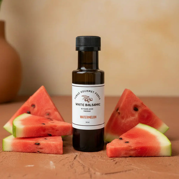 Watermelon White Balsamic Vinegar bottle with fresh watermelon on terracotta surface