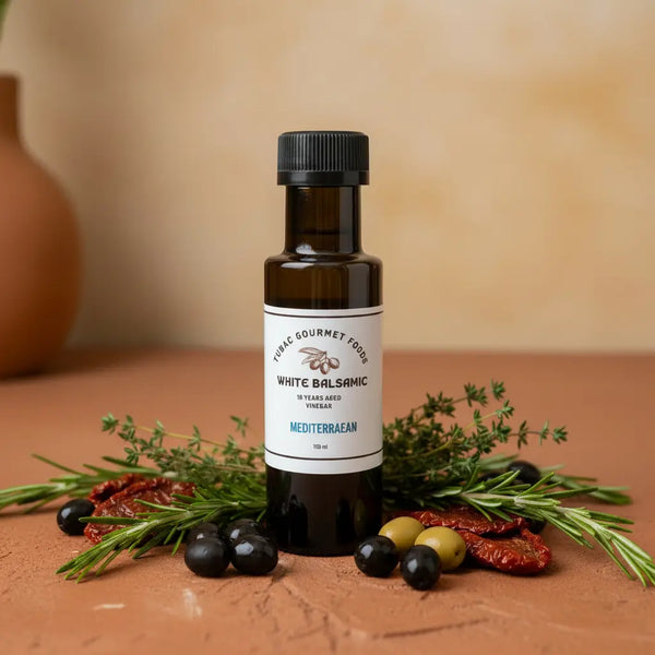 Mediterranean White Balsamic Vinegar bottle with herbs and olives on terracotta surface